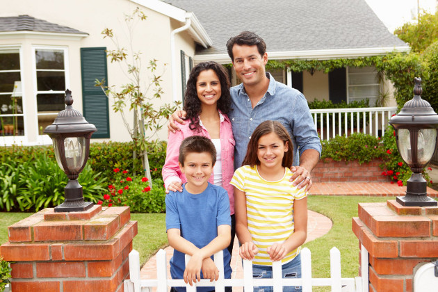 Smiling Family in Front of House