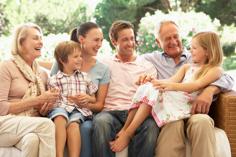 Three Generations of Family Sitting on Sofa Together