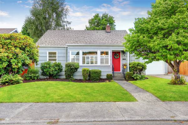 Craftsman style house with blue paint, red door, and nicely manicured yard