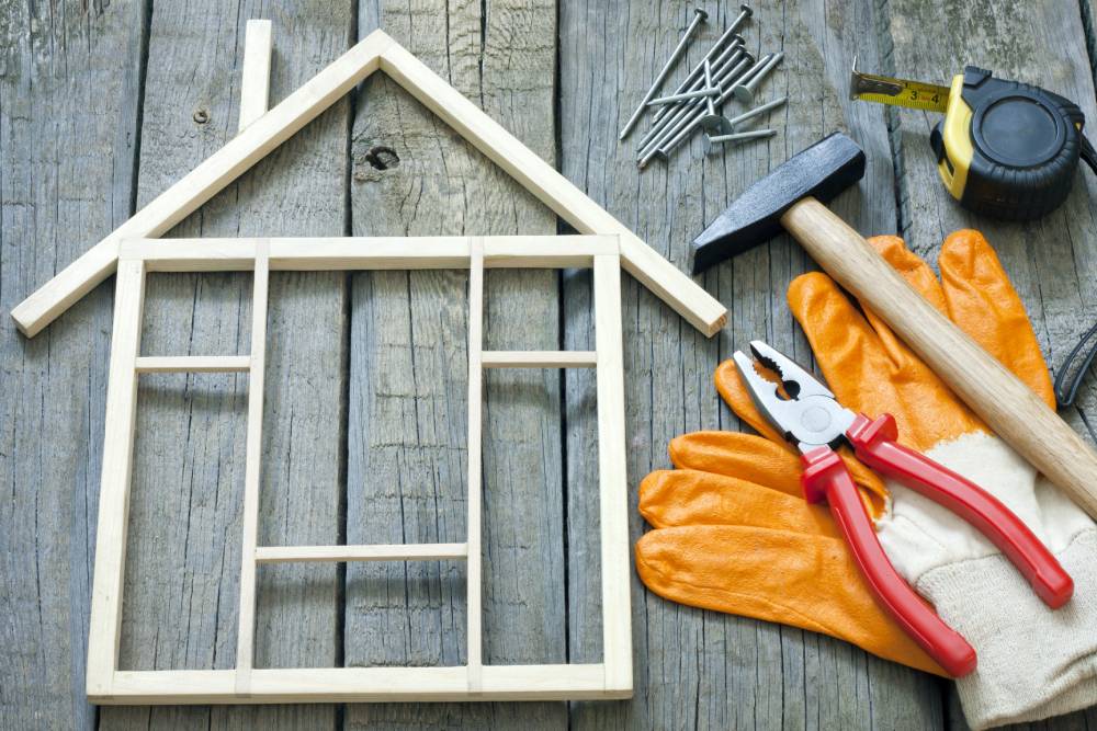 Gloves and other tools on a table next to a small model of the front of a house