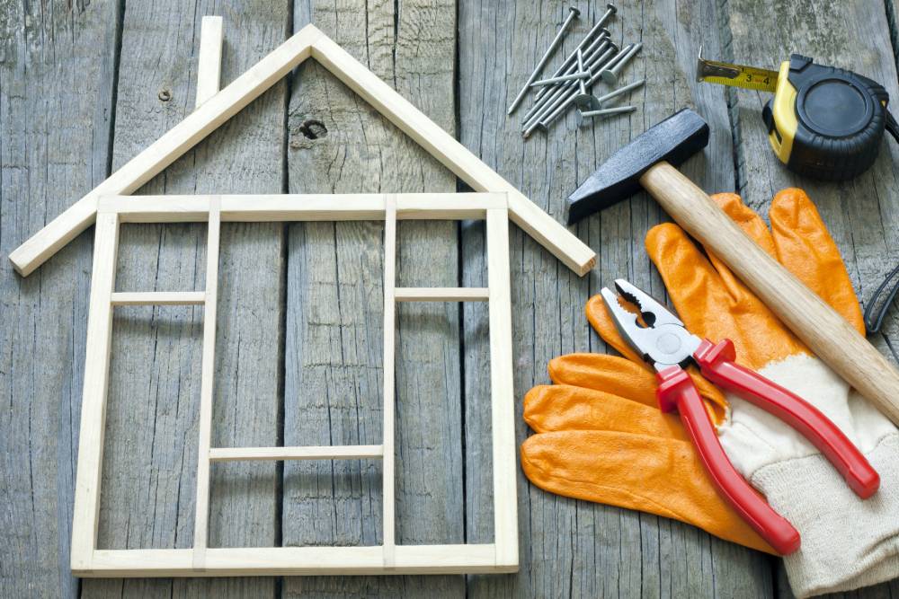 Gloves and other tools on a table next to a small model of the front of a house