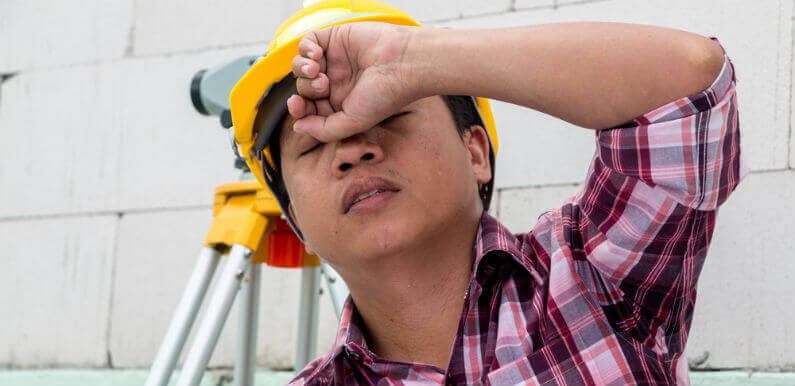 Contractor in Yellow Hard Hat and Red Plaid Shirt with Hand on Head and a Frustrated Expression on Face