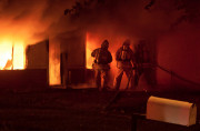 Three Firefighters in Front of Burining Home with Fire Hose