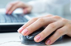 Close up of a woman's hands resting on a mouse and a laptop keyboard