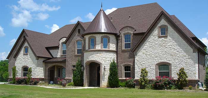 A large brick and stone house featuring a prominent turret, showcasing a classic architectural design.