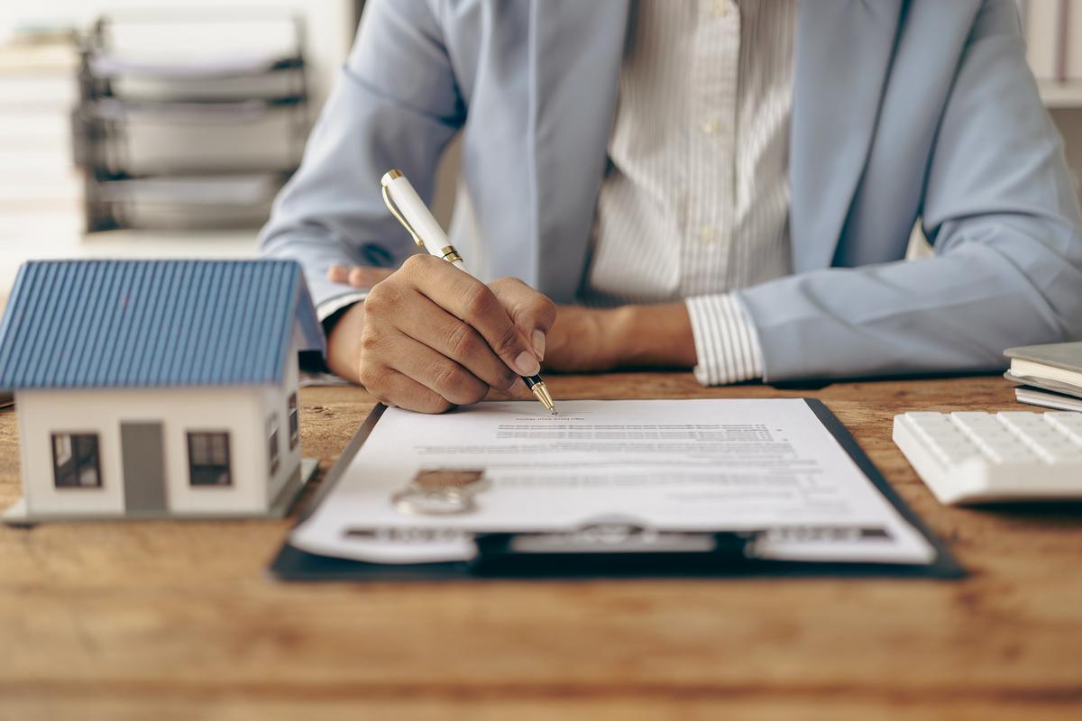 Man signing a contract with model house beside him