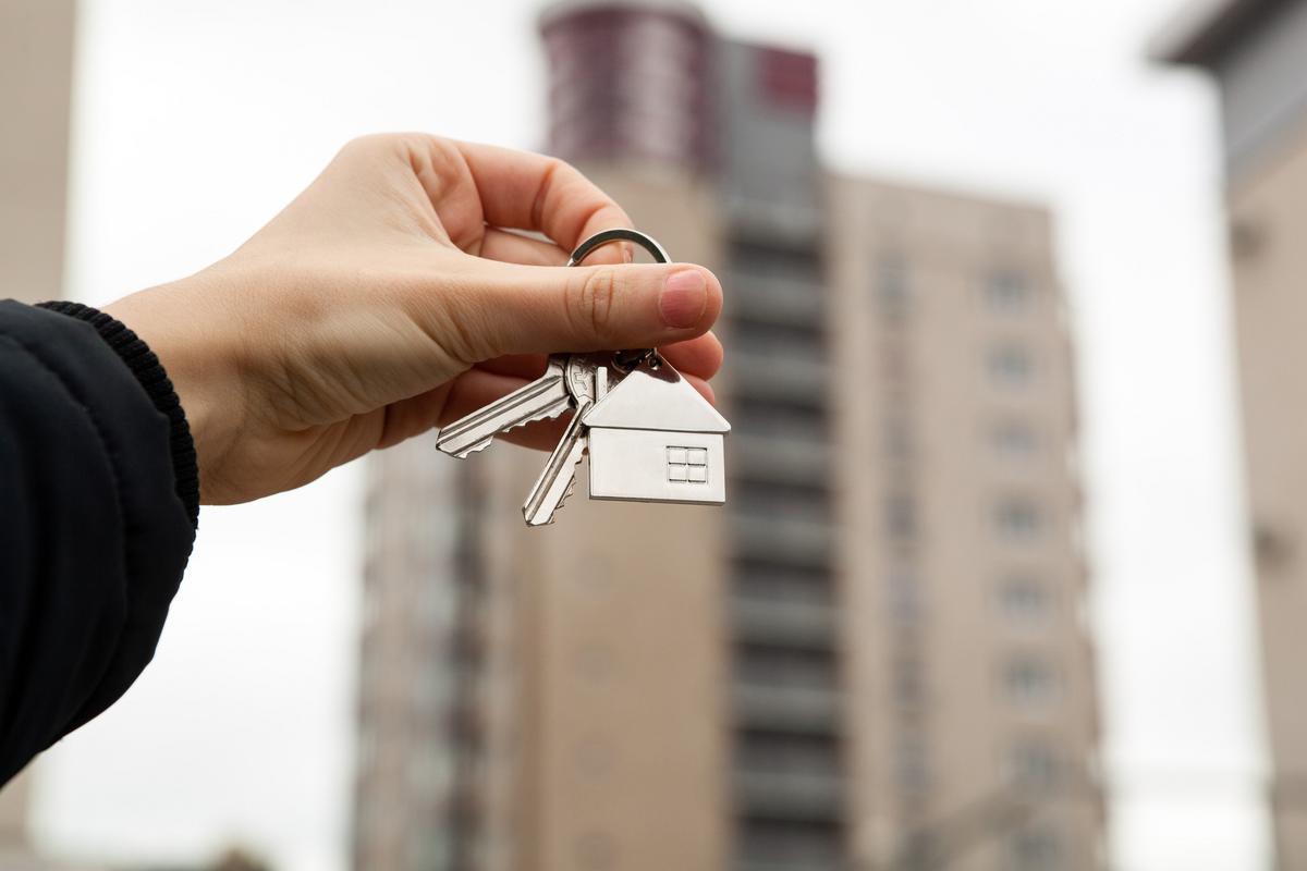 Man holding keys to the house in front of a building