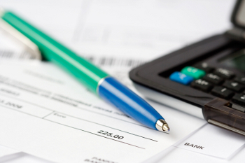 A pen and calculator placed on a check and a receipt, symbolizing financial transactions and record-keeping.