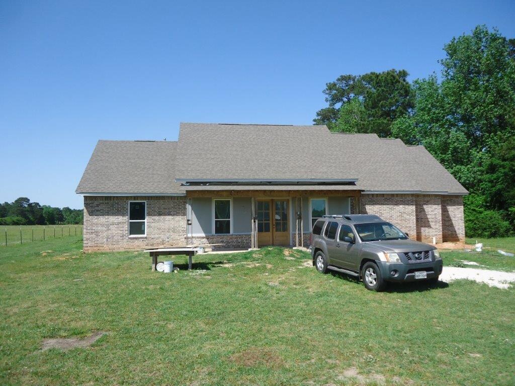 Brick ranch home with a covered porch on an acreage lot.