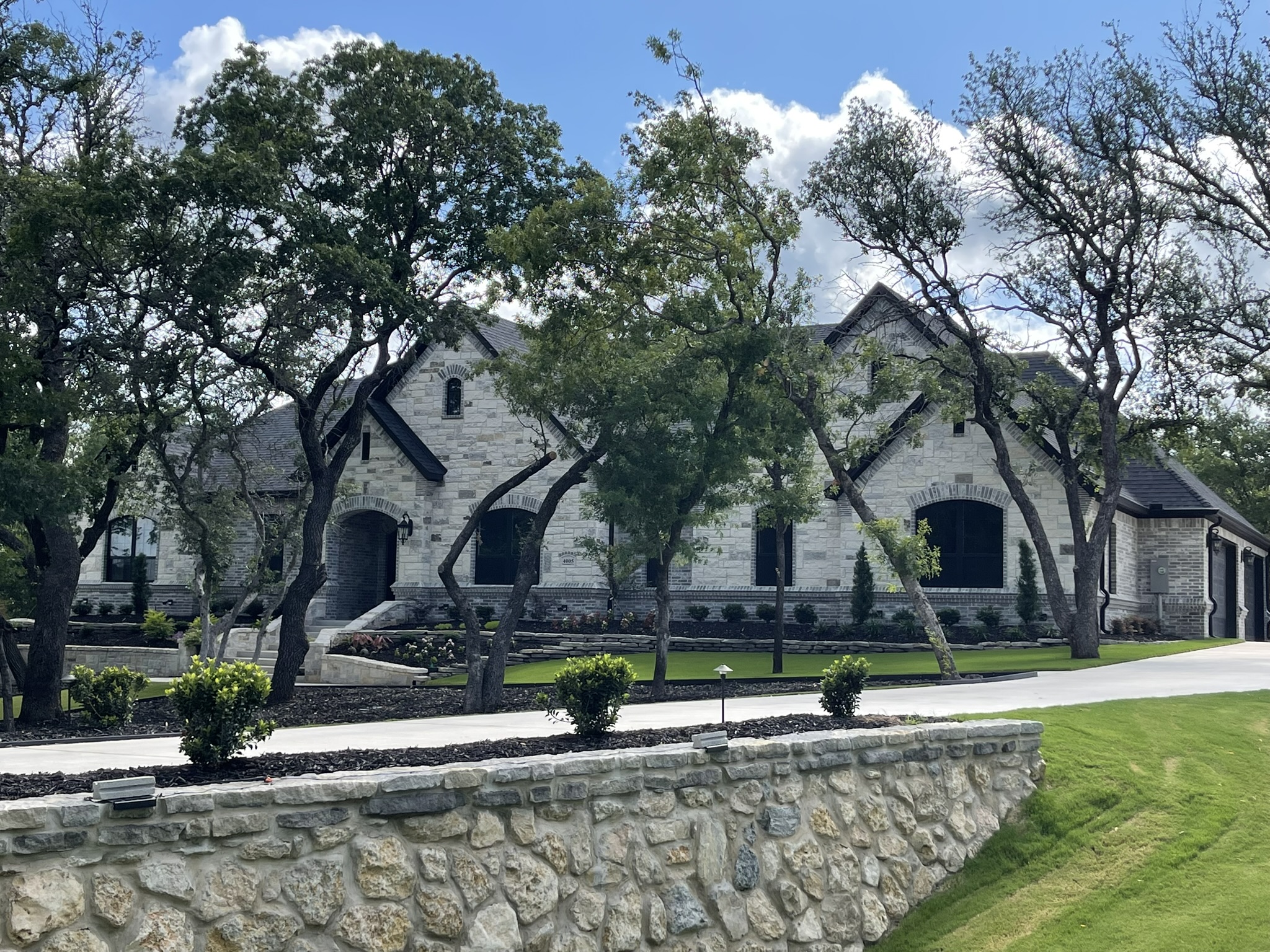 White home with gray roof against blue sky with puffy clouds