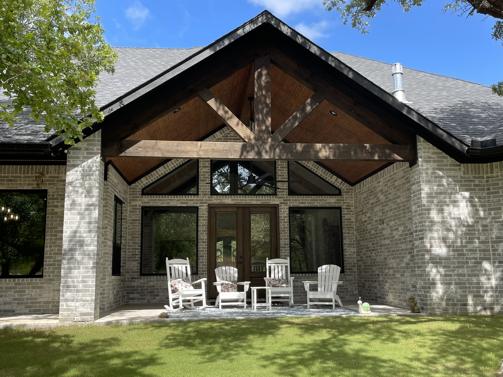 Four white chairs in front of a new home construction stone exterior