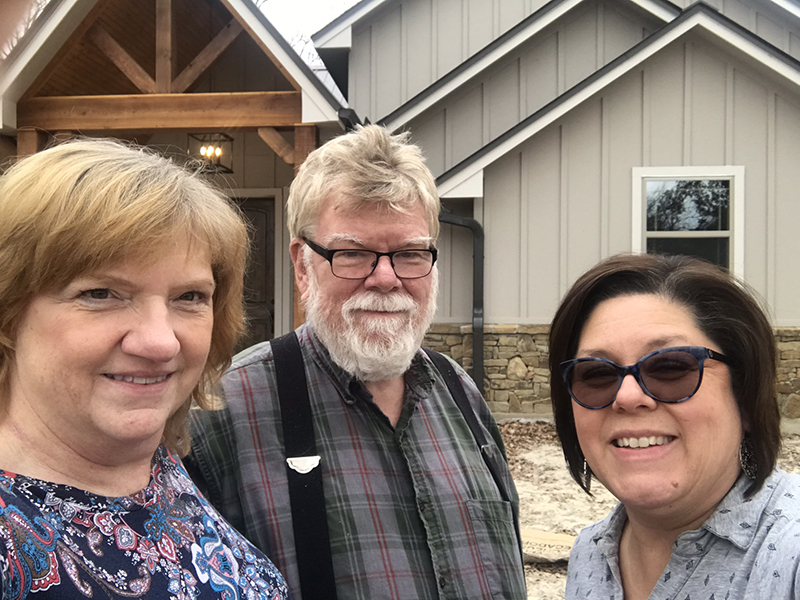 Price family smiling in front of new home.